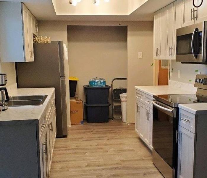 a photo of a smaller kitchen remodel, with white cabinets and wood flooring.